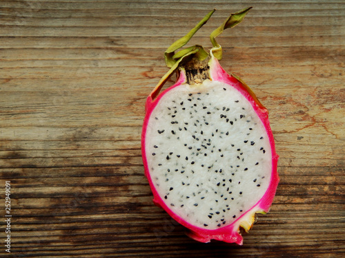 Juicy pink pitaya cut in two pieces on wooden table closeup