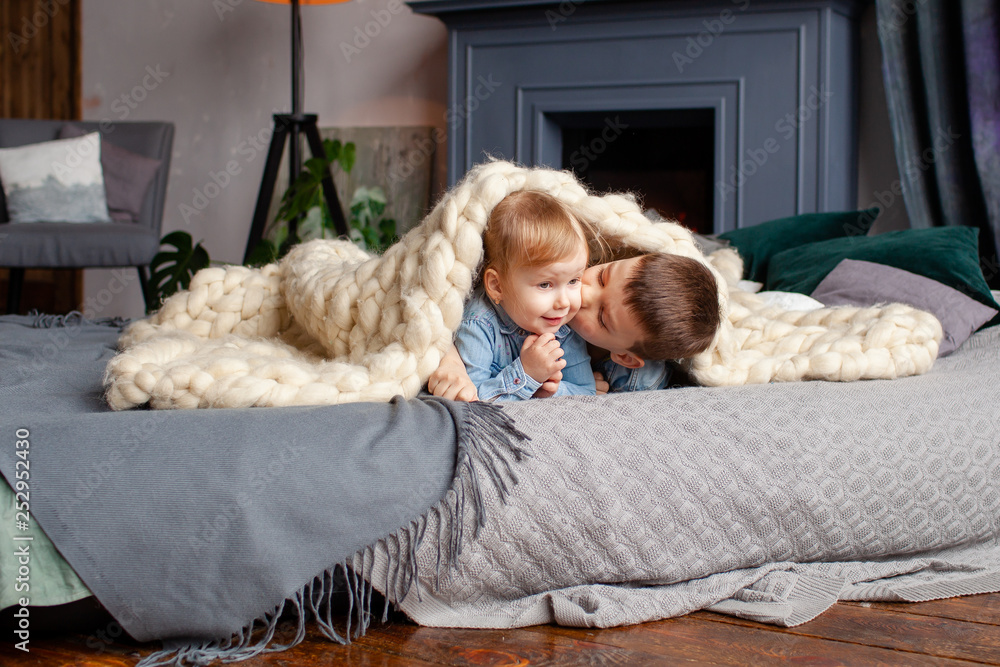 happy cute brother 6 years old and sister 3 years old in a cozy home environment on the bed playing, kissing and hugging, happy family relationships happy cute brother 6 years old and sister 3 years old in a cozy home environment on the bed playing, kissing and hugging, happy family relationships