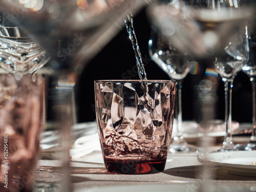 Filling a glass with water, luxury restaurant table