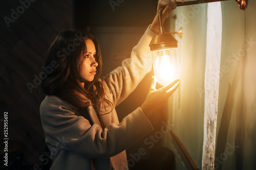 Young beautiful woman holds in her hand a small wall lamp