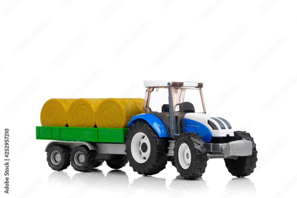 farm tractor toy with hay trailer, isolated on white farm tractor toy with hay trailer, isolated on white
