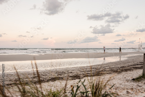 Coppia adulti gioca a racchette sulla spiaggia al mare al tramonto © Giorgio