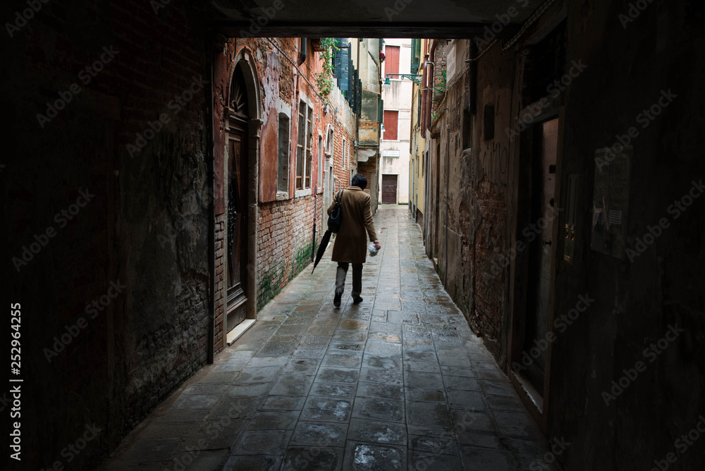 A man walking a a Venetian street. Streets of Venice, Veneto, Italy