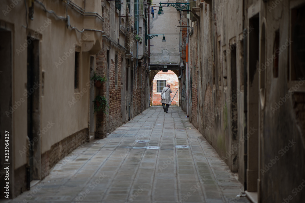 A man walking a a Venetian street. Streets of Venice, Veneto, Italy