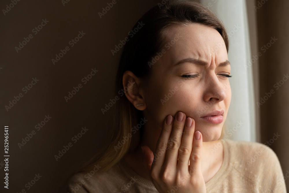 Toothache, and dentistry. Beautiful young woman suffers from terrible severe pain in her teeth, touching her cheek with her hand. Toothache in a woman. Dental care and health concept, dark background Toothache, and dentistry. Beautiful young woman suffers from terrible severe pain in her teeth, touching her cheek with her hand. Toothache in a woman. Dental care and health concept, dark background