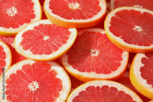 Many sliced fresh ripe grapefruits as background, closeup