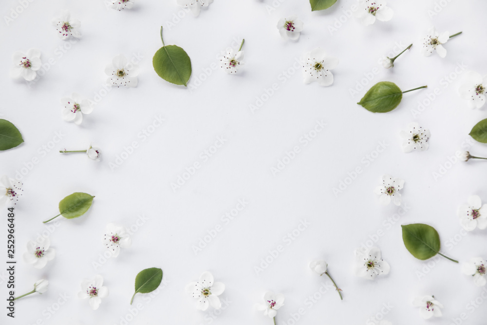 White flowers and green leaves composition pattern on white background with text space. Flat lay, top view