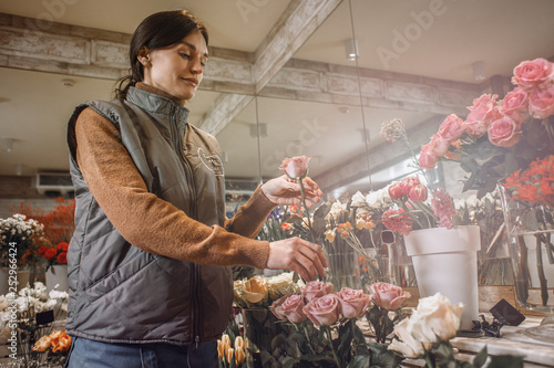 Woman - gardener in the flower shop make bouquet for a holiday. Family flower's business. Lifestyle flower shop. Beautiful flower composition. Love to flower's.Sunlight. Detail. Close up.