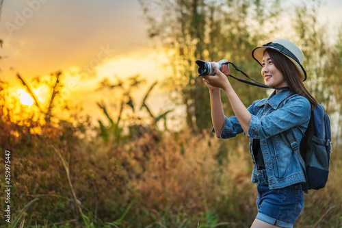 tourist woman taking a photo with camera in nature with sunset