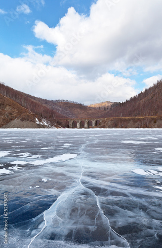 Lake Baikal in winter. View from the beautiful ice with cracks on the Circum-Baikal Railway and the stone arched bridge across the River Bolshaya Krutaya Guba