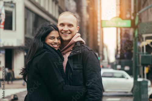Happy young adult multicultural couple in love hugging and smiling on New York City street