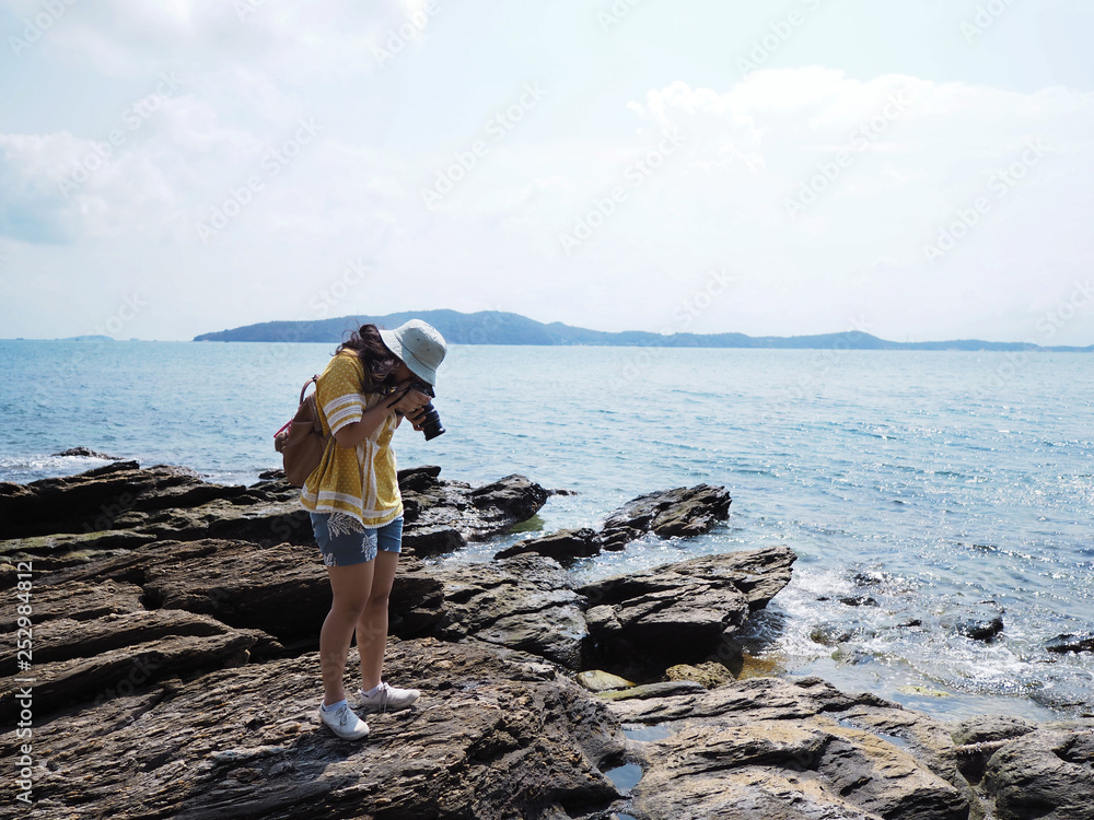Young girl traveler taking photographs of summer beach.