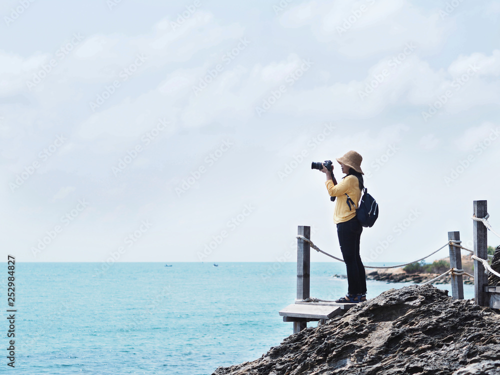 Obraz premium Young girl traveler taking photographs of summer beach.
