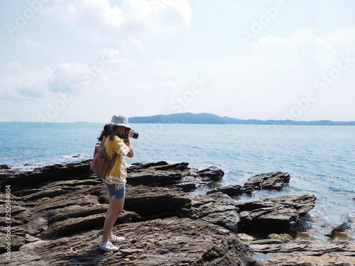 Young girl traveler taking photographs of summer beach.