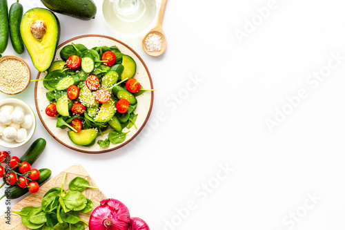 Preparing fresh salad. Vegetables, greens, spices on white background top view copy space