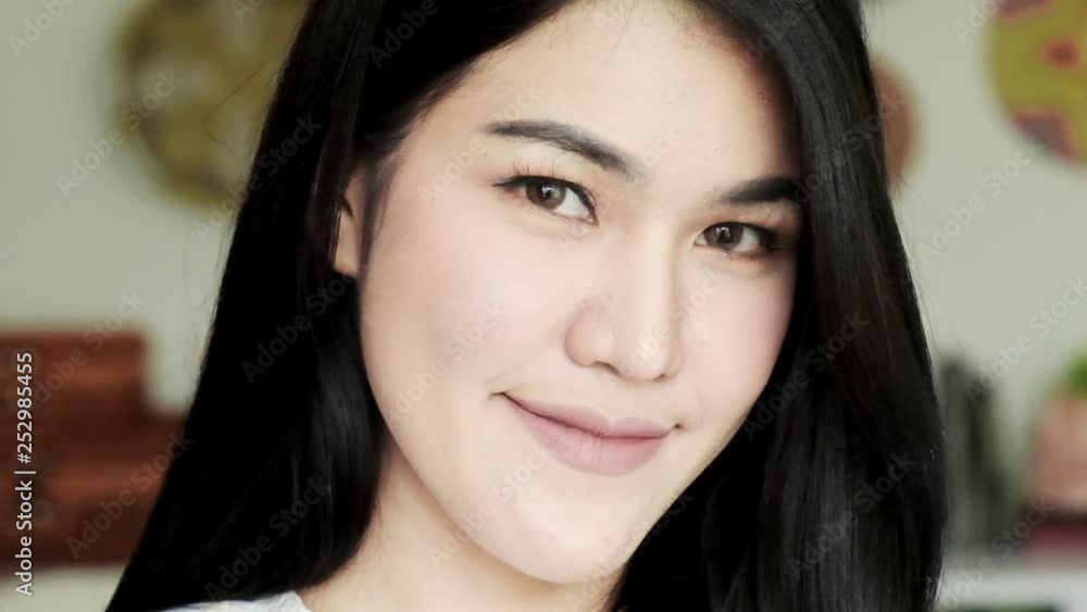 Slow motion of young beautiful asian woman with small smile at camera portait. Young millennial face concept. Slow motion of young beautiful asian woman with small smile at camera portait. Young millennial face concept.