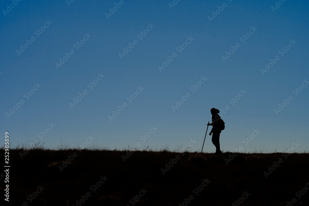 Silhouettes of hikers with backpacks enjoying sunset view from top of a mountain Silhouettes of hikers with backpacks enjoying sunset view from top of a mountain