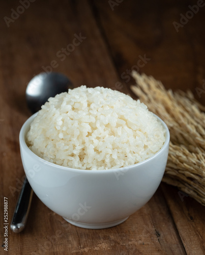 Steam White rice in white ceramic bowl on wood table for healthy meal.