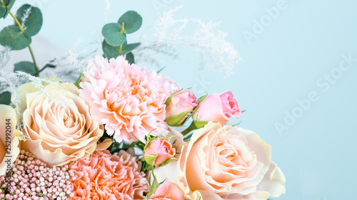 Beautiful bouquet with pink carnations and roses close-up on a blue background.