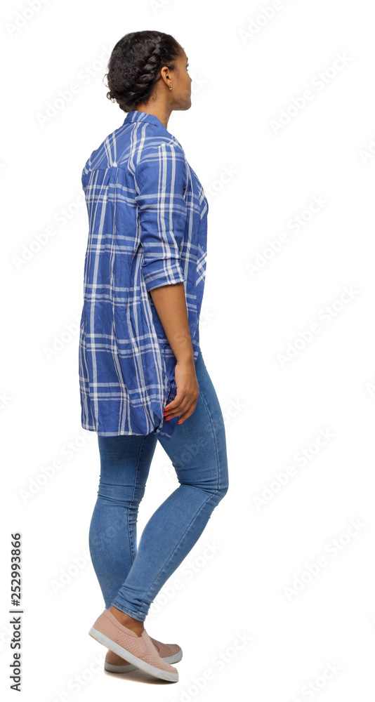 Side view of a young black girl walking in jeans and a checkered shirt. Side view of a young black girl walking in jeans and a checkered shirt.