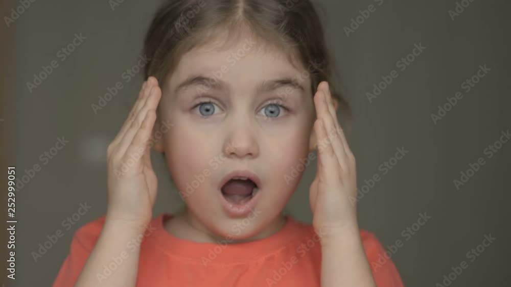 Cute little girl open her face with hands. Girl looks and is surprised ...