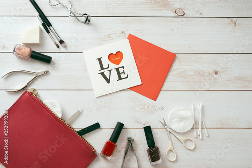 white card with a pattern in the form of heart, Manicure set and nail polish on wooden background. Valentine's Day. flatlay