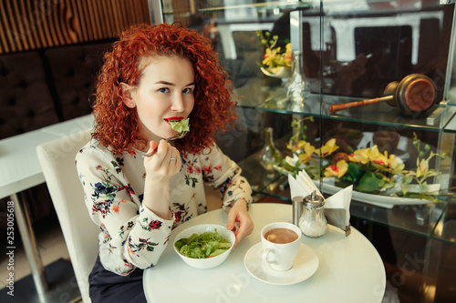 A young attractive woman sitting in a cafe with a salad