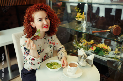A young attractive woman sitting in a cafe with a salad
