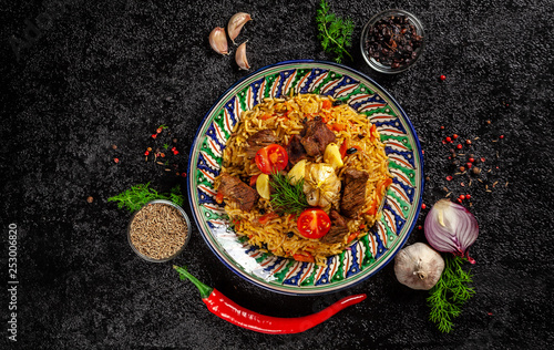 The concept of oriental cuisine. National Uzbek pilaf with meat in a cast-iron skillet, on a wooden table. background image. top view, copy space, flat lay