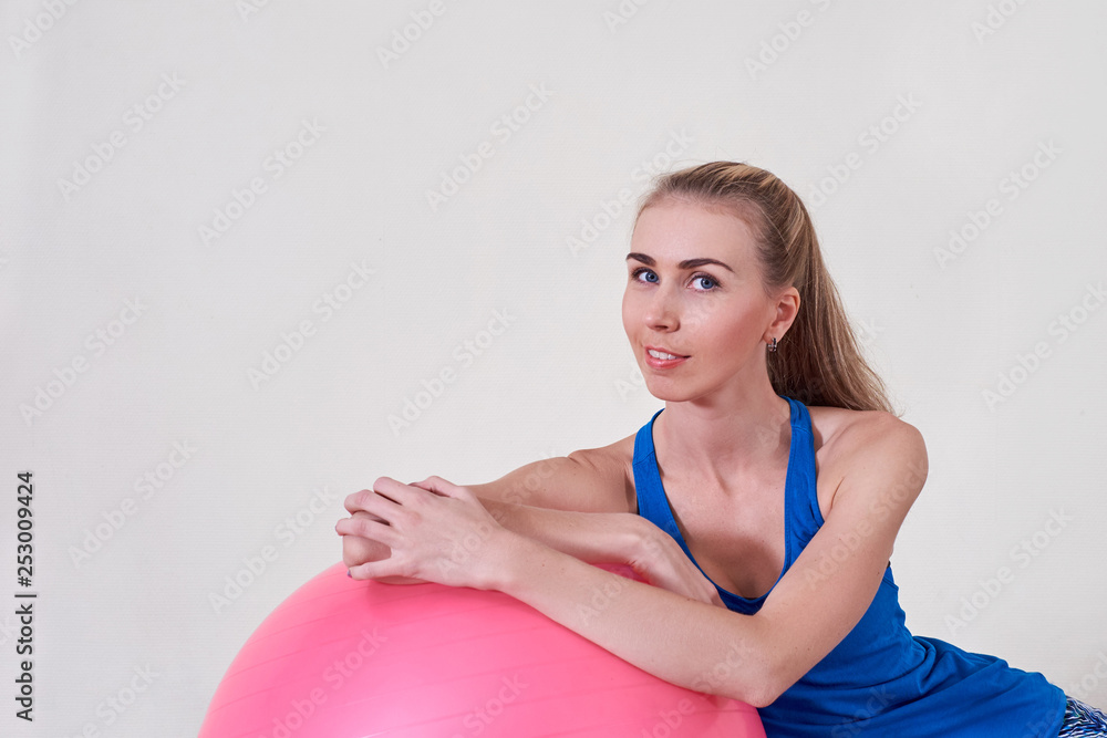 Athletic woman makes exercises on a fitness ball , indoors gym.