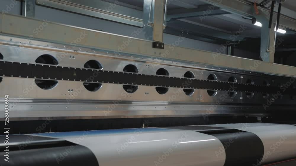 Massive printhead passing by. Large scale rolls for advertising and commercial fairs. Robotic machinery, automation concept, occupation and economy. Global supply and delivery. Massive printhead passing by. Large scale rolls for advertising and commercial fairs. Robotic machinery, automation concept, occupation and economy. Global supply and delivery.