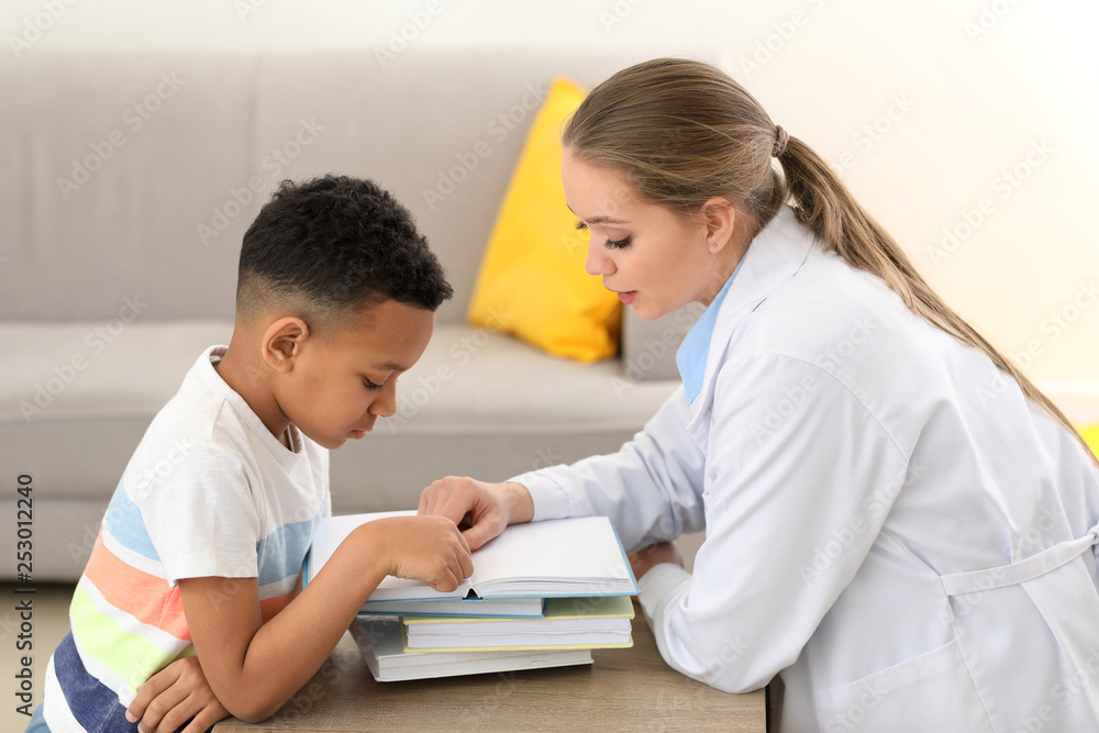 Little boy with speech therapist reading book in office Little boy with speech therapist reading book in office