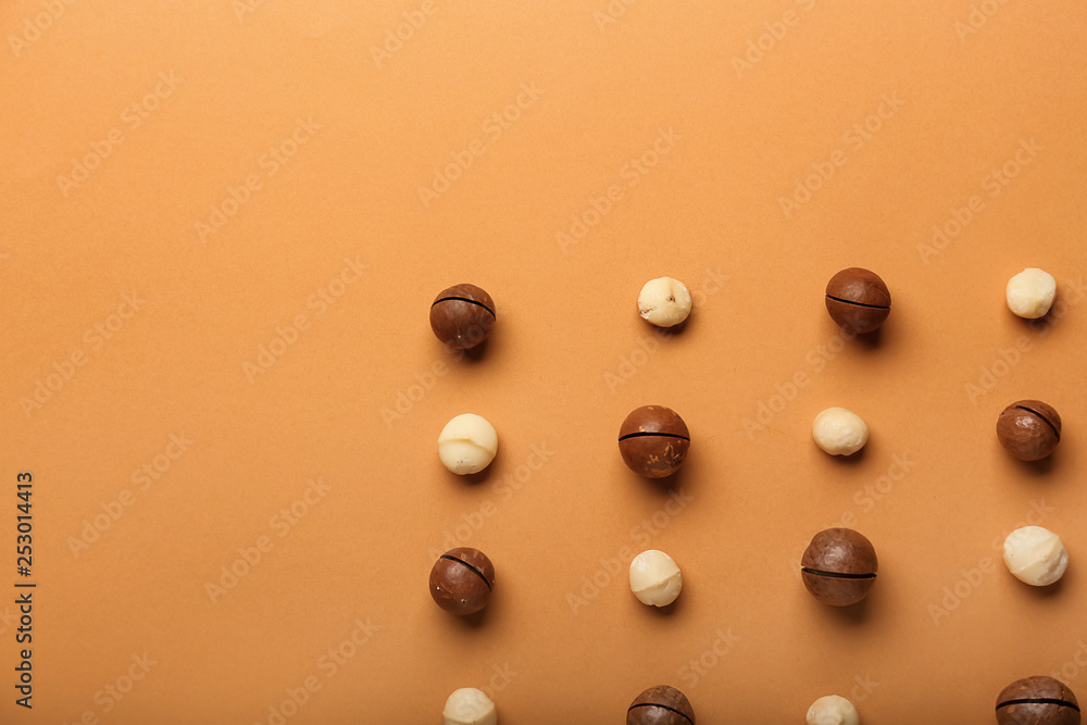 Many macadamia nuts on color background