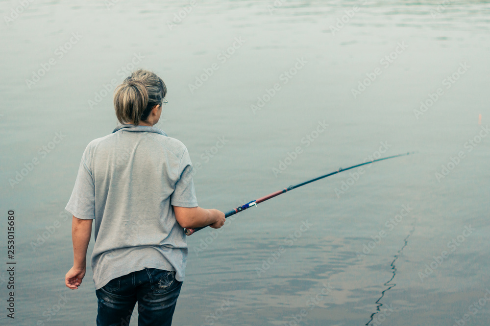 A woman is busy fishing. Fisherwoman holds the bait in anticipation of the catch A woman is busy fishing. Fisherwoman holds the bait in anticipation of the catch