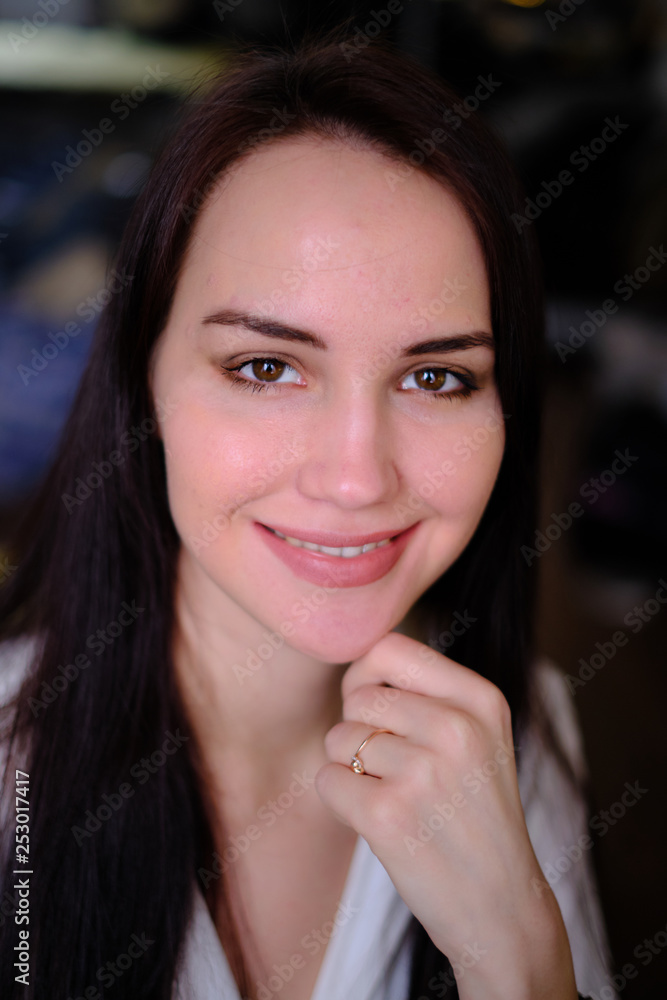 A young beautiful, pretty girl looks into the lens. Close-up. Brown hair. Big brown eyes with a make-up, lips of soft tone. In ordinary clothes. Blurred background. A young beautiful, pretty girl looks into the lens. Close-up. Brown hair. Big brown eyes with a make-up, lips of soft tone. In ordinary clothes. Blurred background.