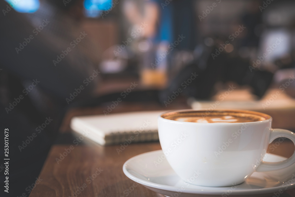 Cappuccino cup on the table with blur people in coffee shop background, vintage tone Cappuccino cup on the table with blur people in coffee shop background, vintage tone
