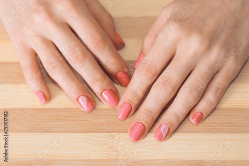 Female hands with a manicure on a wooden background.