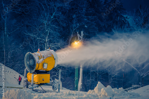 snow making machine on the hill working on the ski run in evening