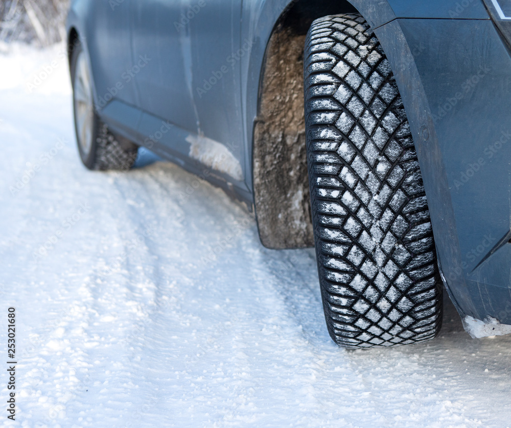 Car winter tyre on the snow. Slippery wintry road with unstudied tires.