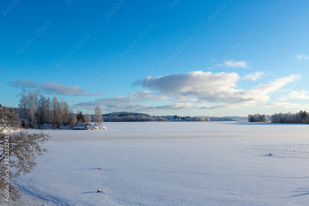 Wintry landscape on a cold winter morning in Finland. Lake view and blue sky.