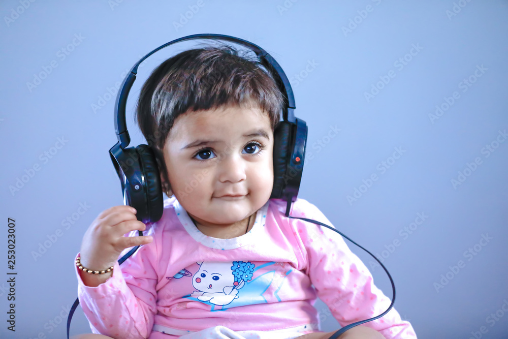 Φωτογραφία Cute Indian/asian small girl listening to music on headphones