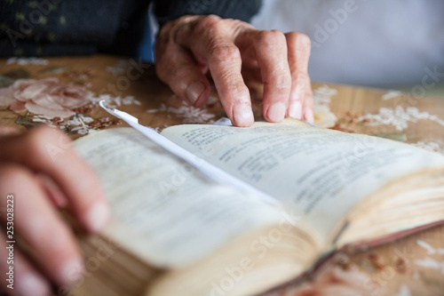Old woman hands on the open prayer book.