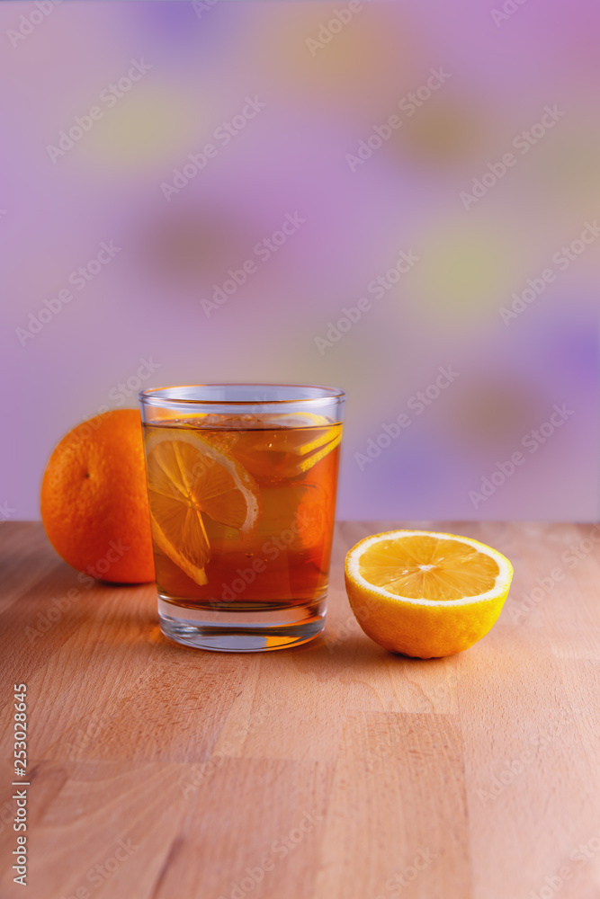 a glass of delicious refreshing lemonade with fruit on a blurred color background a glass of delicious refreshing lemonade with fruit on a blurred color background