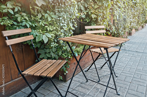 one table and two chairs from wooden boards stand on the street in city s cafe in summer