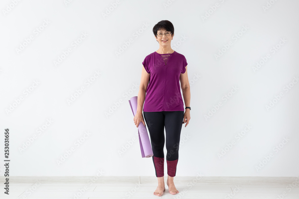 Yoga, people concept - Portrait of a middle age woman after yoga with her mat on white background with copy space