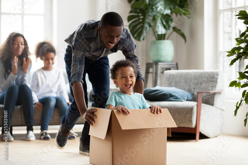 Happy black family play with kids moving to new home