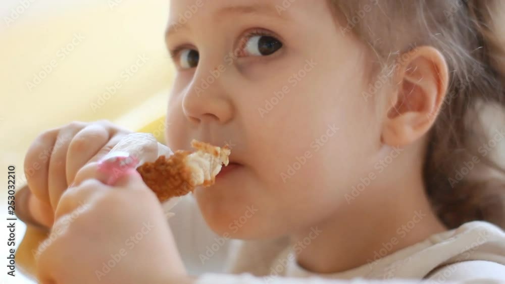 Baby girl eating nuggets closeup. Portrait child who eats fast food. Baby girl eating nuggets closeup. Portrait child who eats fast food.