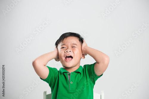 Young boy and closed eyes covering ears with hands