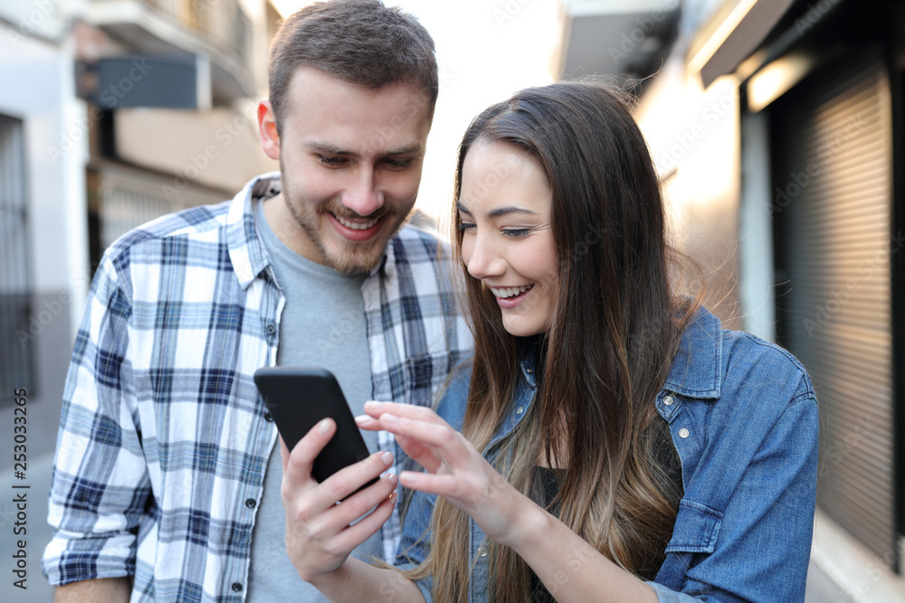 Couple are checking smart phone content in the street Couple are checking smart phone content in the street