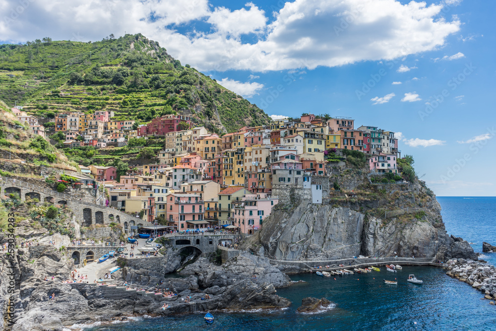 Italy, Cinque Terre, Manarola, Cinque Terre, a group of people standing next to a body of water with Cinque Terre in the background